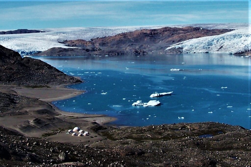 En mitad de la imagen dos enormes icebergs procedentes de los glaciares del fondo. Se puede observar nuestro campamento de tiendas esféricas donde puede albergar hasta 80 personas, comparen con los témpanos. Fiordo de Qaleralliq