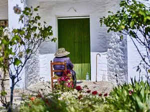 Anciana tomando el sol a la puerta de su casa rodeada de flores./ Víctor Gibello